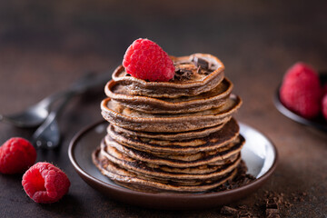 Wall Mural - Vegan carob chocolate pancakes with raspberries on a plate, closeup view