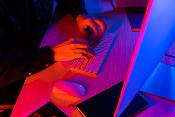 cropped view of programmer using computer near notebook on table