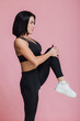 © kalinichenkod - sporty woman stretching her legs and looking at camera on pink background