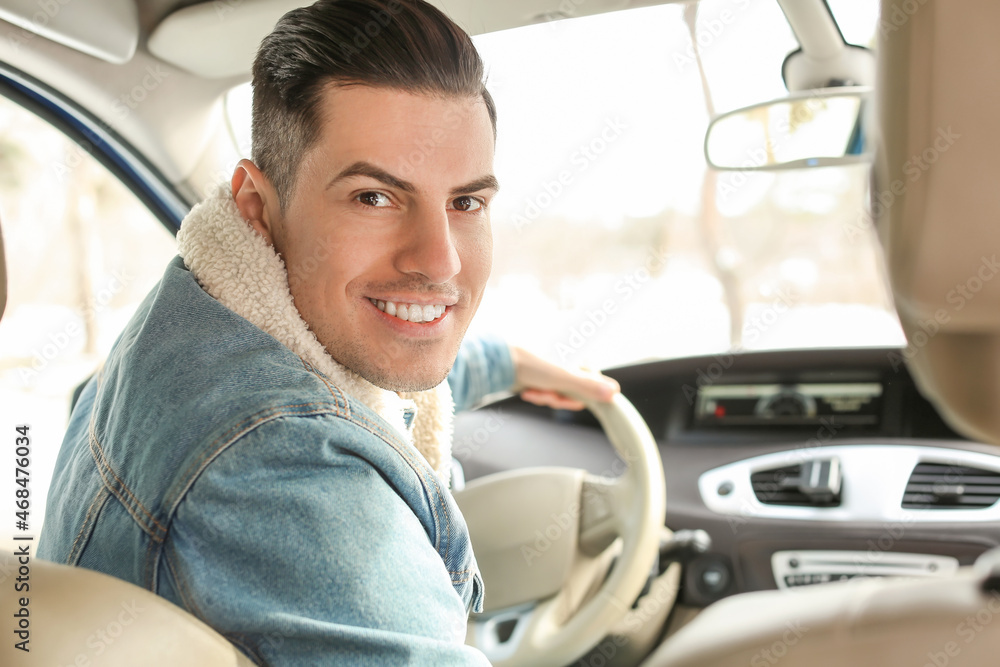 Young man sitting in car on winter day