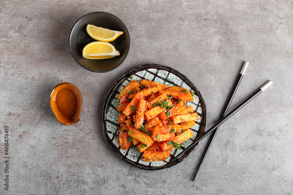 Plate with honey chilli potato on grunge background