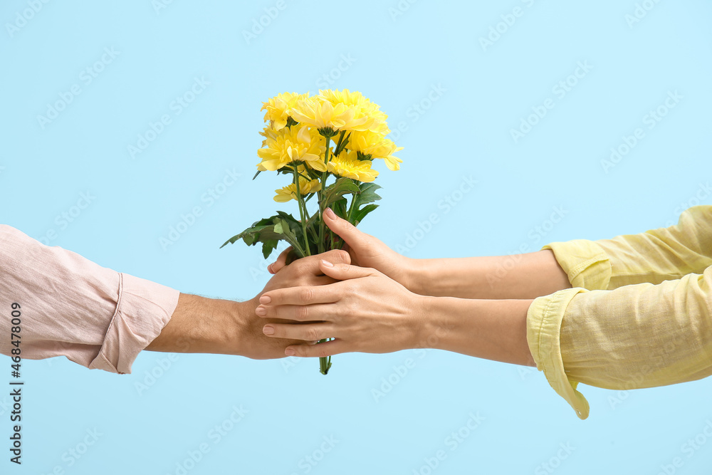 Man giving flowers to woman on blue background