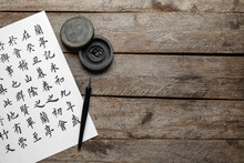 Tools For Calligraphy And Paper With Asian Hieroglyphs On Wooden Background