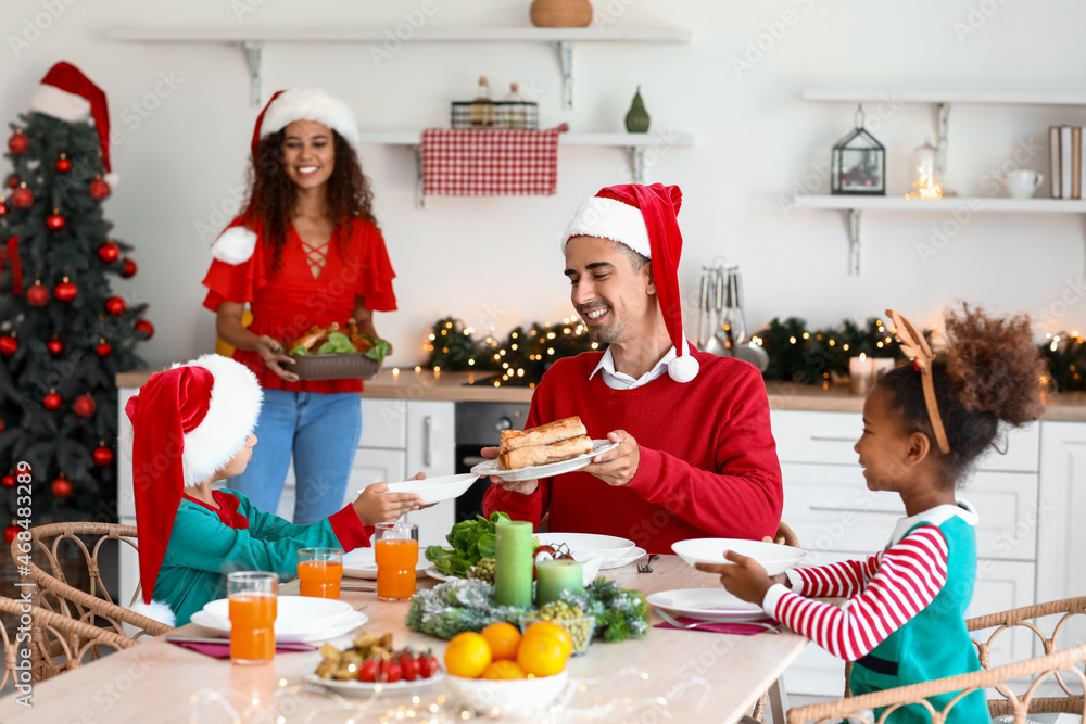 Mother setting table for Christmas dinner with her family in kitchen