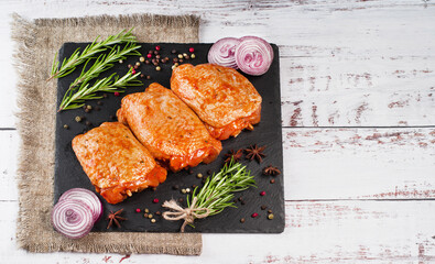 Three pieces of chicken thighs marinated in red sauce on a kitchen cutting board, on a light background, banner. Top view.Convenience food, quick cook, semi-cooked food.Free space, copy space.