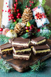 © Carey - Nanaimo bars on a wooden board surrounded by Christmas decorations.