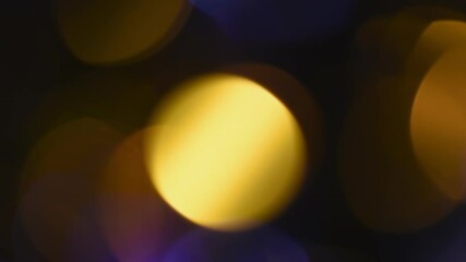 Wall Mural - Bright golden bokeh motion. Beautiful round bokeh of gold and blue colors movement on a black background. Can be used as a background or overlay.