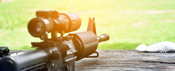 Wall Mural - Airsoft gun or bb gun with white plastic bullets on wooden floor, soft and selective focus on airsoft gun.