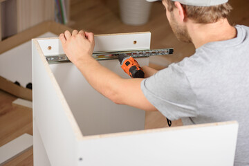 Wall Mural - A man assembles a new table with a screwdriver. Handyman