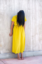 Adult Woman With Long Black Hair Barefoot And Standing Leaning On A Wall With Her Head Tilted Forward And Her Hair Covering Her Face