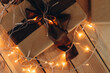 a gift on the background of a decorated Christmas tree, bokeh from a garland, a festive atmosphere