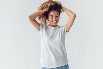 Smiling woman with lush curly hair in white blank t-shirt on a white background. Mock-up.