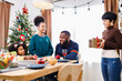 © chayantorn - African American family surprising together with a gift on Christmas day while dinner. Merry Christmas. Happy family.
