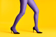© GVS - Female legs in purple tights and high heels shoes on yellow background
