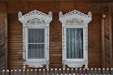 Wall Mural - Ornamental windows with carved frames on vintage brown wooden rural house in Maydakovo village, Ivanovo region, Russia. Building facade. Russian traditional national folk style in wooden architecture