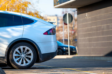 Wall Mural - a side fragment of the rear of a modern car in a parking lot near an office building on a sunny day