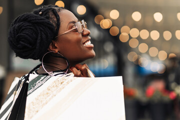 Wall Mural - Attractive happy African American young woman shopping on Black Friday shopping mall with packages, Shopping concept