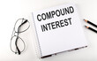 © Iryna - Notepad with text COMPOUND INTEREST . White background. Business concept