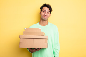 Wall Mural - young handsome man shrugging, feeling confused and uncertain. package boxes