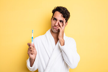 young handsome man feeling bored, frustrated and sleepy after a tiresome. bathrobe and toothbrush concept