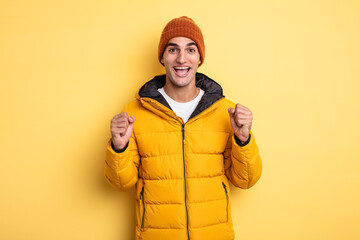 young handsome man feeling shocked,laughing and celebrating success. winter concept