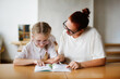 © natalialeb - a teacher and a girl student, a child at school at a desk learning to read, a teacher and a student learn letters, working together with a teacher, with a tutor. Child and tutor in a lesson at school
