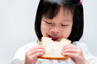 Cute baby girl eats bread on white background. Child enjoy and biting food.
