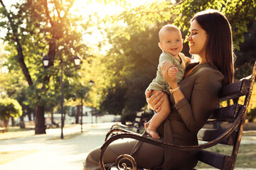 Canvas Print - Young mother with her cute baby on bench in park