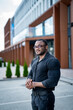 © Vadim - Handsome dark-skinned man standing near building. Fit man in tight shirt and glasses looking straight ahead. Man with big biceps in a tight shirt at business center.