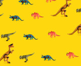 Fototapeta Dinusie - pattern made with dinosaur toy against yellow illuminating background. surreal modern abstract art