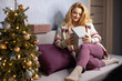 © rubchikova - Portrait of a young woman with a christmas gift on a sofa at home