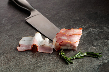 Wall Mural - Bacon with rosemary on a kitchen knife.