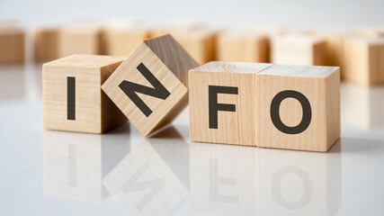 four wooden blocks with the letters info on the bright surface of a gray table, business concept
