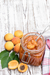 Wall Mural - Apricot jam in a glass jar on white wooden table