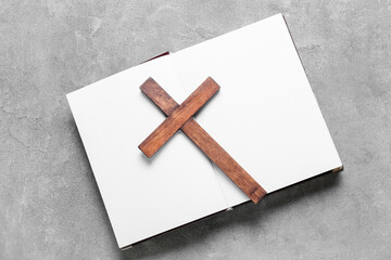 Open book with wooden cross on grunge background