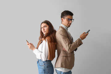 Canvas Print - Quarreled young couple using mobile phones on light background