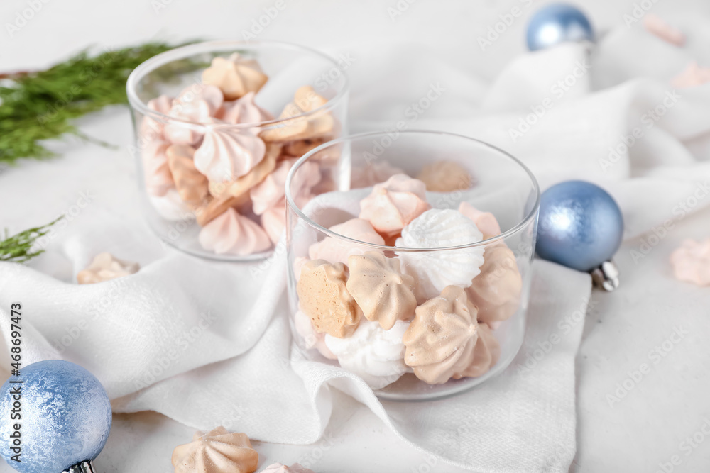 Glass bowls with tasty meringues on white background