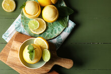 Plate and bowl with tasty ice creams in lemon peels on color wooden background