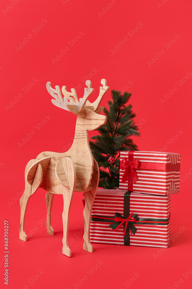 Wooden reindeer with Christmas tree and presents on red background