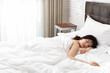 © Blue Jean Images - Young Chinese woman sleeping on bed