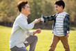 © Blue Jean Images - Happy Chinese father and son playing on meadow