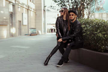 Sexy couple posing on a bench and looks away in the street