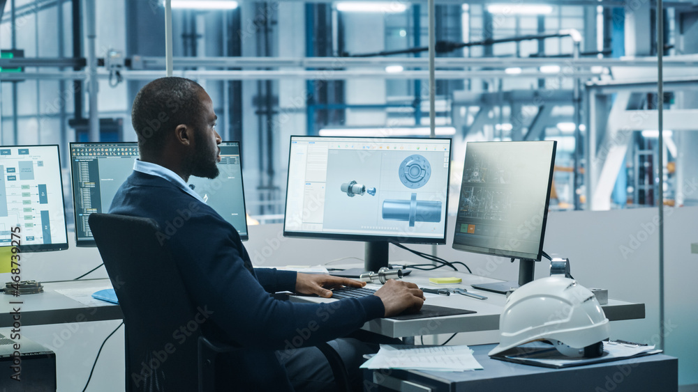 Car Factory Office: Black Engineer Working on Desktop Computer, Screens Show CAD Software with 3D Component, Monitoring of Automated Robot Arm Assembly Line Manufacturing High-Tech Electric Vehicles