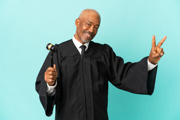 Wall Mural - Judge senior man isolated on blue background smiling and showing victory sign