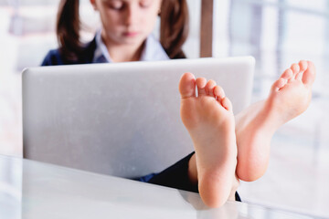 Wall Mural - Humorous image of beautiful young business girl working in office with bare feet. Selective focus on feet.