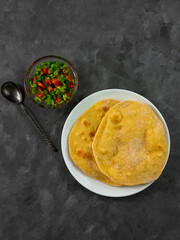 Homemade corn flatbread with cilantro greens tomato salsa. Handmade mexican tortillas vegetable salad. Traditional Indian Punjabi Makki ki roti bread plate top view Wheat flour dough authentic cuisine