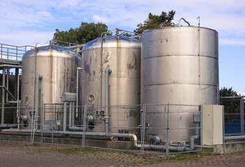 Canvas Print - Metal fence around an industrial facility with tanks andpipes