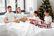 family, winter holidays and people concept - happy mother, father and two daughters in pajamas with christmas gifts in bed at home