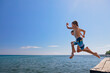 © Tropical studio - Young happy couple have fun at sea beach. Children run, jump high into water. Popular travel destination. Family summer vacation with kids at tropical island.