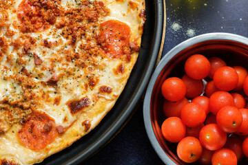 Wall Mural - Top view of a delicious gourmet pizza on a pan and cherry tomatoes in a bowl